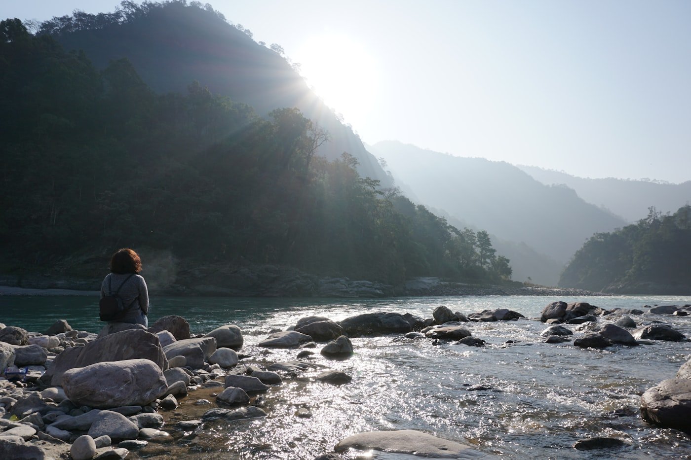 A person sitting on a rock beside a river