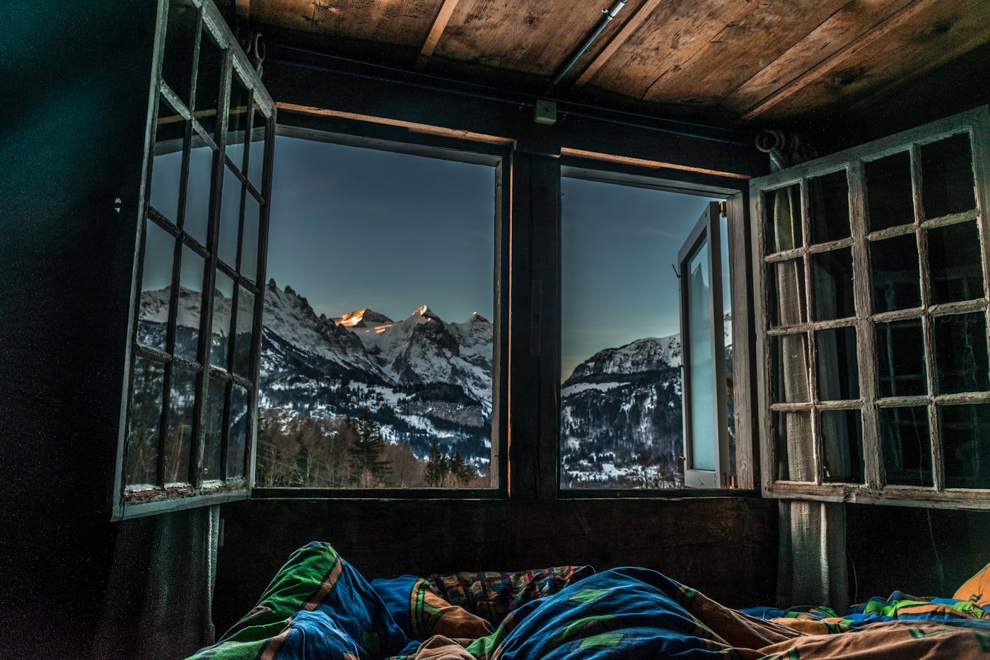 A simple bedroom with mountains visible through the window