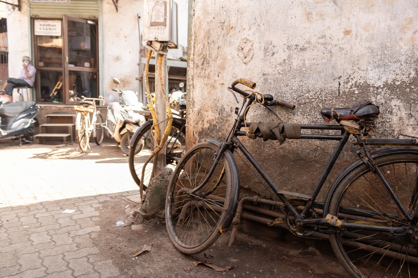 A two wheeler leaning against a weathered wall